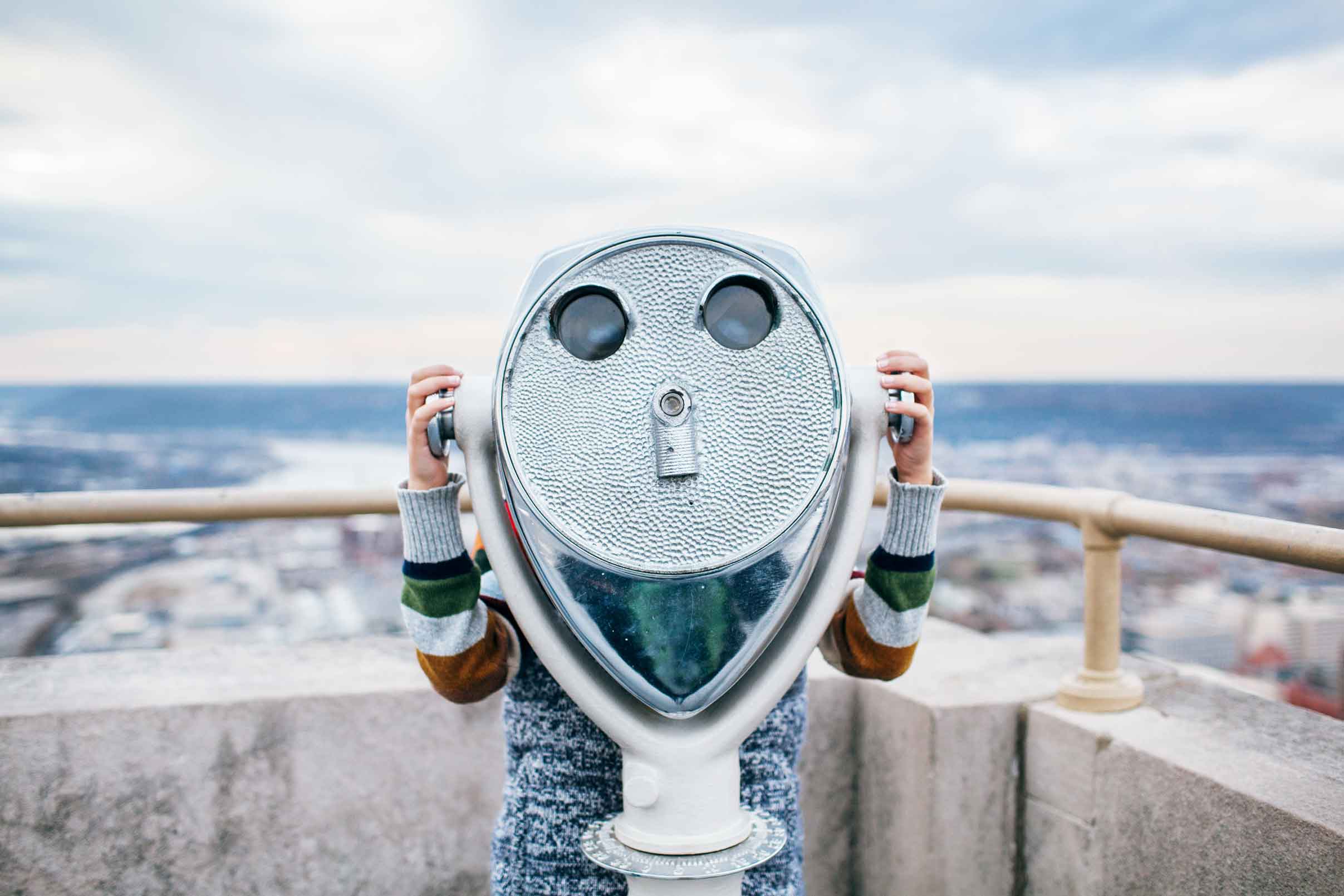 Person on a rooftop looking at the landscape through a viewer