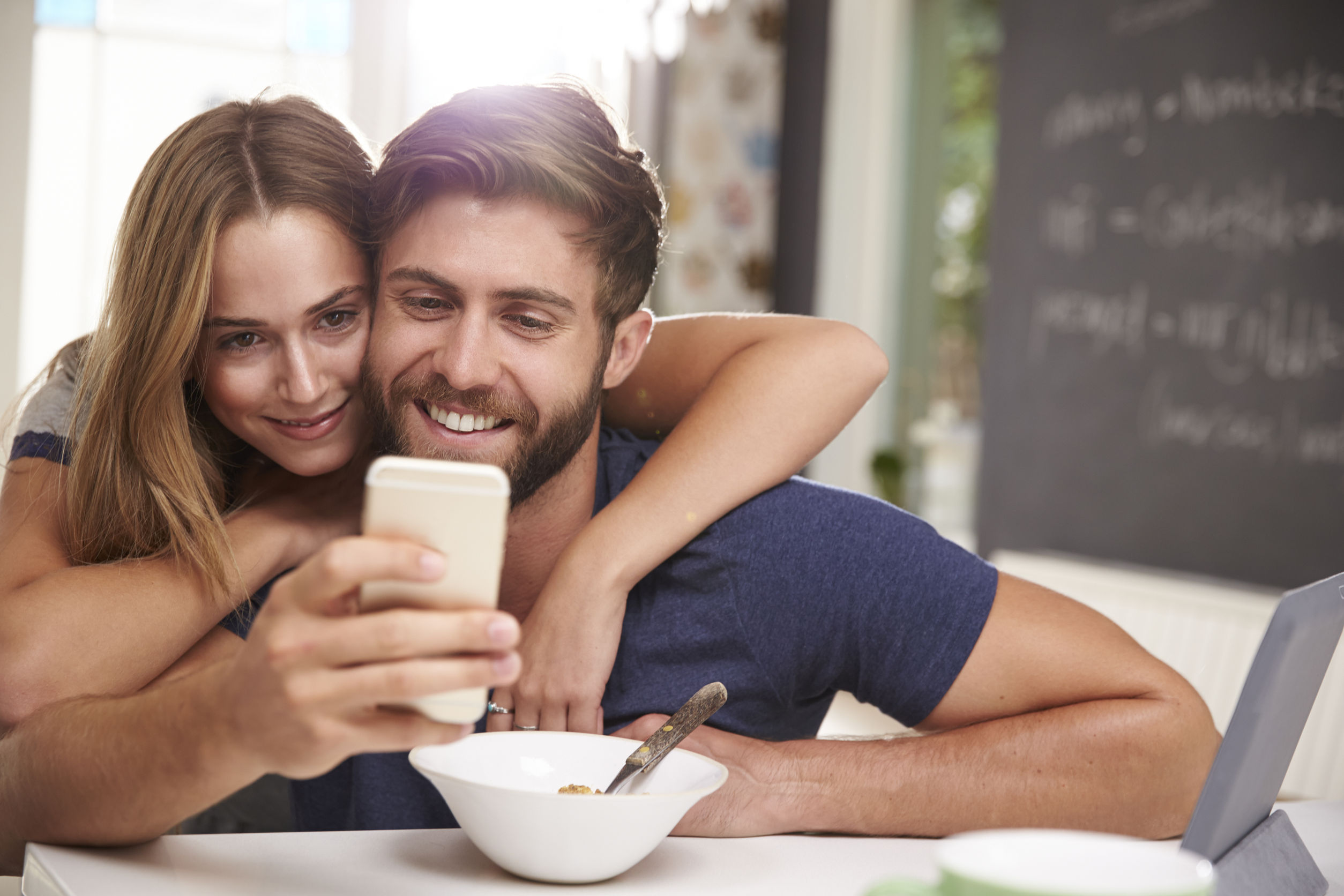 Pareja Joven Pareja joven, sentados en su cocina mirando el telefono movil