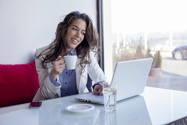 Mujer Tomando Cafe Mujer sonriente tomando un taza café por la mañana y usando una laptop